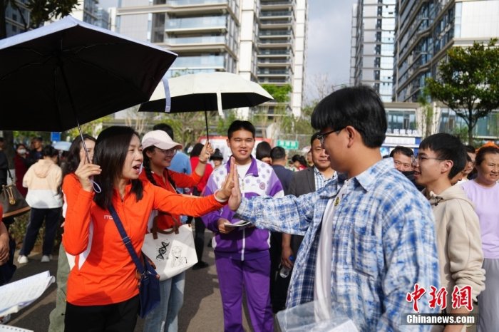 6月7日，云南昆明，老师与考生击掌加油。中新社记者 刘冉阳 摄